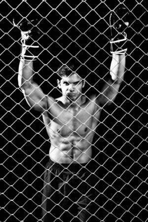 Mixed martial artist posed behind chain linkの写真素材