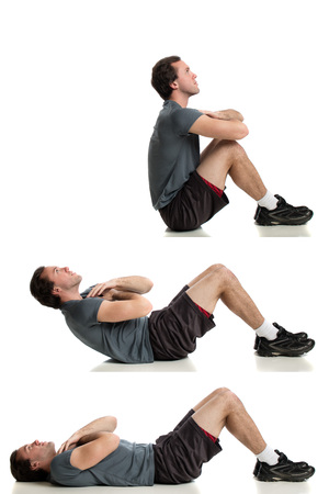 Young adult man doing sit ups. Studio shot over white.の写真素材