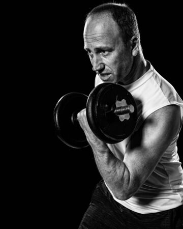 Bicep curl exercise with dumbbell. Studio shot over black.の写真素材
