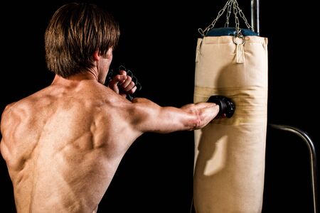 Young adult martial artist with heavy bag. Studio shot over black.の写真素材