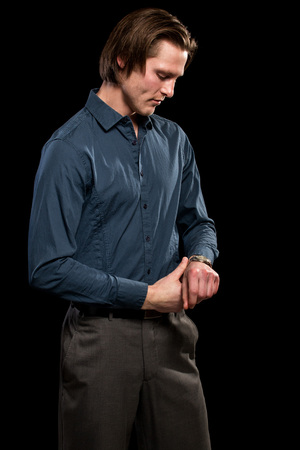 Man in blue shirt and grey slacks. Studio shot over black.の写真素材