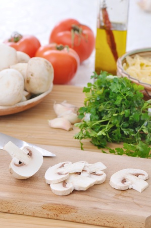 table with raw food ingredients and slieces of white mushroomsの写真素材