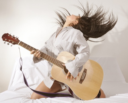 portrait of a girl is feeling free and playing guitar in a roomの写真素材