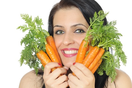 face of a young woman holding fresh carrots closed to her faceの写真素材