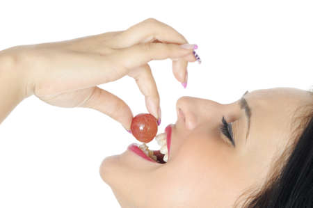 smiling young woman eating fresh grape, on whiteの写真素材
