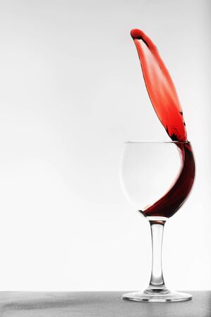 red wine splashing in a glass on a grey backgroundの写真素材