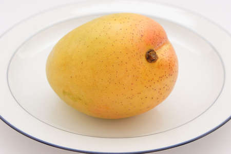 A whole mango on a plateの写真素材