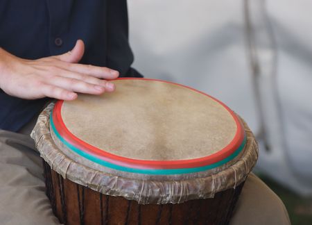 Musician playing a drum held between his legs