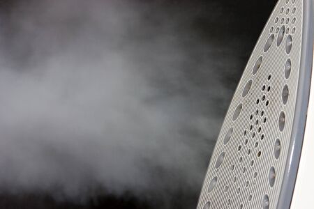 An iron with steam against a dark backgroundの写真素材
