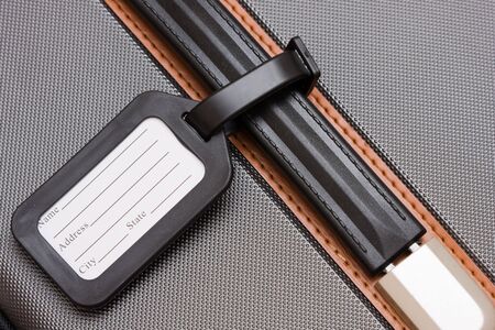 A black luggage tag on a handle on a bagの写真素材