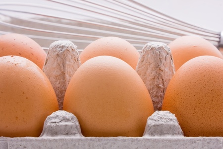 A half dozen carton of eggs with a whisk - the mortal enemy of the eggの写真素材
