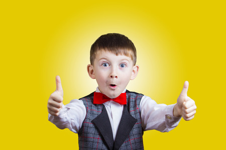Excited Surprised  little boy with thumb up gesture isolated over yellow background.の写真素材