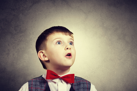 Surprised little boy looking up with mouth open isolated over yellow background.の写真素材