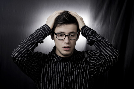 Stressed, frustrated, depressed portrait of a young student, man, holding his hands up on head isolated on grey background.Facial expression,の写真素材