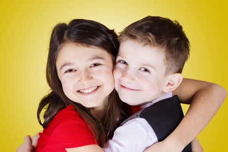 Happy brother and sister hugging over yellow background.Love, Family, Friendshipの写真素材