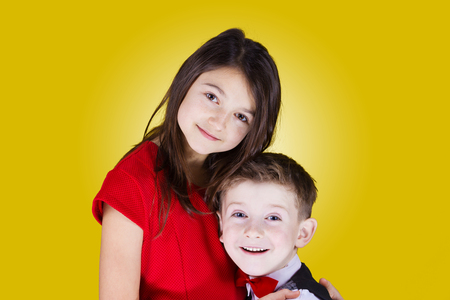 Happy brother and sister hugging over yellow background.Love, Family, Friendshipの写真素材