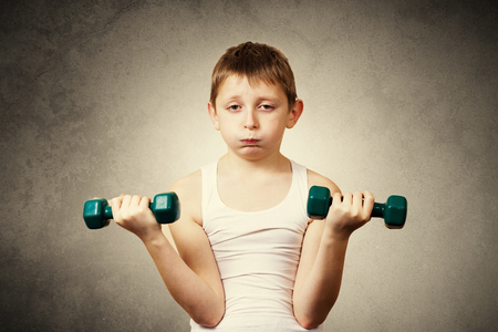 Tired, Bored, upset little boy with dumbbell.Facial expression, Sport.の写真素材