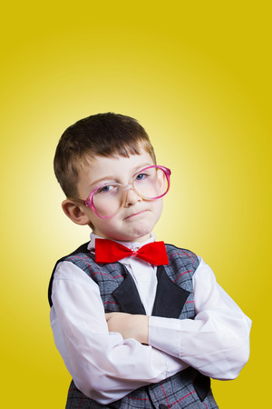 Serious Confident little boy nerd isolated over yellow background.の写真素材