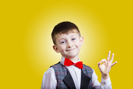 Funny Little boy making Ok sign over yellow backgrounの写真素材