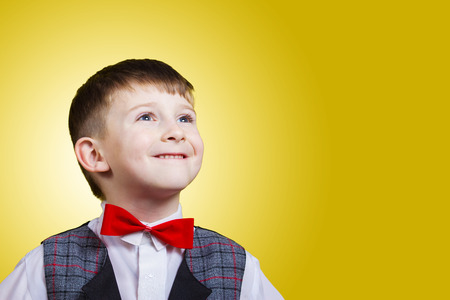Smiling Happy Joyful beautiful little boy looking up.Closeup Studio Portrait isolated on yellow background.の写真素材