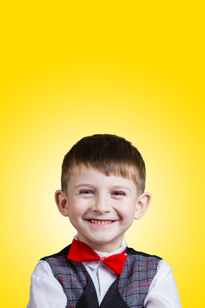 Smiling Happy Joyful beautiful little boy  looking at camera.Closeup Studio Portrait isolated on yellow background.の写真素材