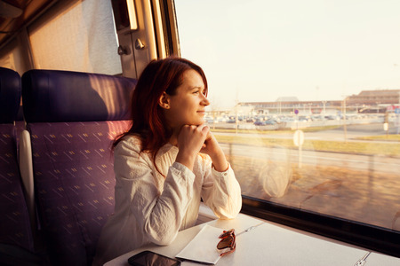 Young woman traveling looking out the window while sitting in the train.の写真素材