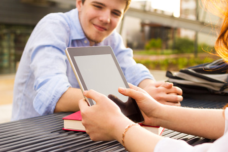 Young student woman taping on tablet in a city on university bench .Young student  outdoors with tablet.Life style.Cityの写真素材
