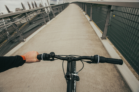 Close-up image of  handlebar  bike in park, face is not visible.Young man riding bike in city park over a bridge.View from bikers eyes.の写真素材