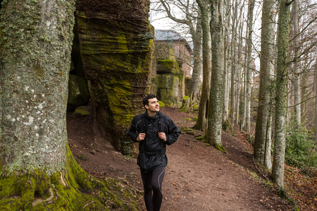 Young Man,Student hiking in forest.Man hiker smiling happy portrait looking up enjoying nature on foggy day during a trekking trip. Back of a young man outdoors in nature on a hiker path in forest.の写真素材