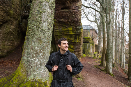 Young Man,Student hiking in forest.Man hiker smiling happy portrait looking up enjoying nature on foggy day during a trekking trip. Back of a young man outdoors in nature on a hiker path in forest.の写真素材