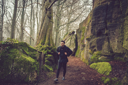Young Man,Student hiking in forest.Man hiker smiling happy portrait on foggy day during a trekking trip. Back of a young man outdoors in nature on a hiker path in forest.の写真素材