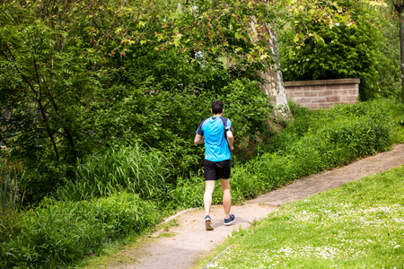 Healthy running runner man workout in a city park. Jogging male fitness model working out training  on park road.の写真素材