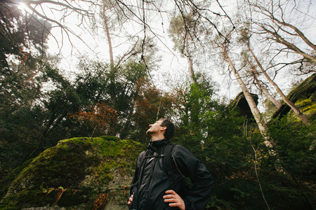 enjoying nature on foggy day during a trekking trip. Back of a young man outdoors in nature on a hiker path in forest.の写真素材