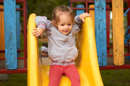 Cute little girl Preschooler is sliding on the Playground in parkの写真素材