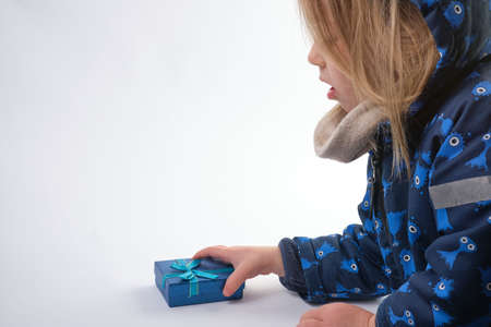 dressed for winter little girl pick up a blue gift boxの写真素材