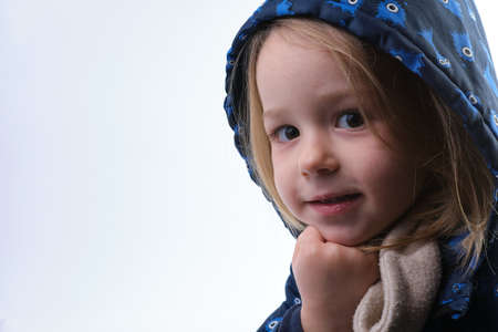 Adorable preschool girl dressed for winter hood with hands under chin poseの写真素材