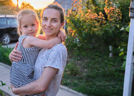 portrait happy mother holding Cute young daughter smiling sunlight home outdoorの写真素材