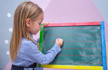 Cute happy pre school little girl write with chalk on blackboard Homeschooling