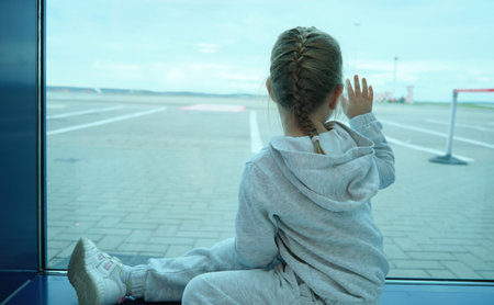 Little girl children looking waiting through window hand on airplane in airportの写真素材