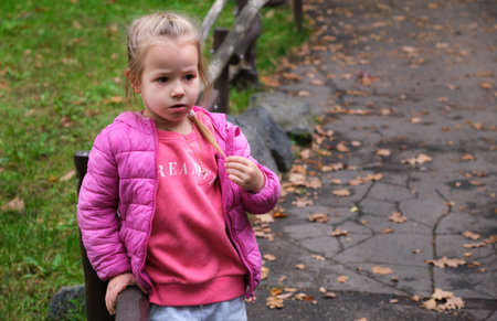 Thoughtful puzzled confused little girl child thinking park pathway alley autumn
