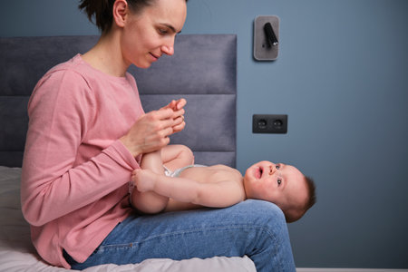 loving mother playing little baby boy new born talking in bedroom while enjoying special moment of motherhood togetherの写真素材