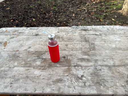 A red water bottle sits on a weathered wooden surface. The shot evokes health, nature, and sustainability. Ideal for hydration, lifestyle, and outdoor themesの写真素材