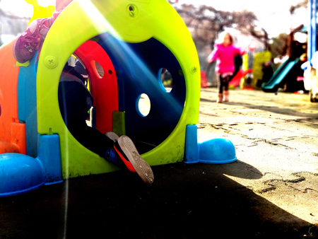 Little child playing and hiding in a colourful toy in a playground, fun and play concept. Hide and...