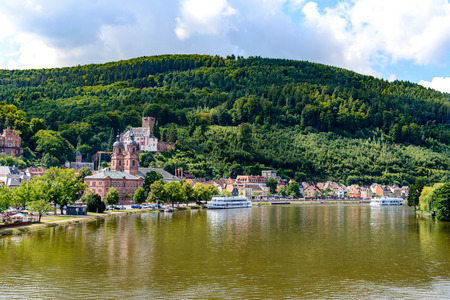 Beautiful postcard View on old german town Miltenberg am Main river, Castle, St. Jacob catholic church, cruise ships, mountain with wood in Odenwald,  Bavaria, Germanyのeditorial素材