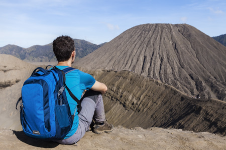 Young male adult traveler watching the crater and the caldera of the active Bromo volcano, East Java, Indonesiaの写真素材