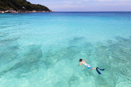 Snorkeller swimming in pristine clear turquoise tropical sea water on paradise islandの写真素材