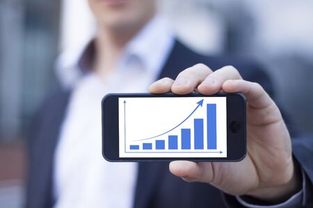 Successful businessman proud to display improvement on smartphoneの写真素材