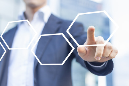 Businessman touching hexagonal button in workflow with honeycomb patternの写真素材