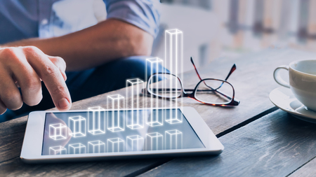 Businessman analyzing growing 3D AR chart floating above digital tablet computer screen, showing...