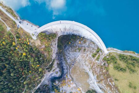 Hydroelectricity generated from water dam and reservoir lake in Swiss Alps mountains to produce...